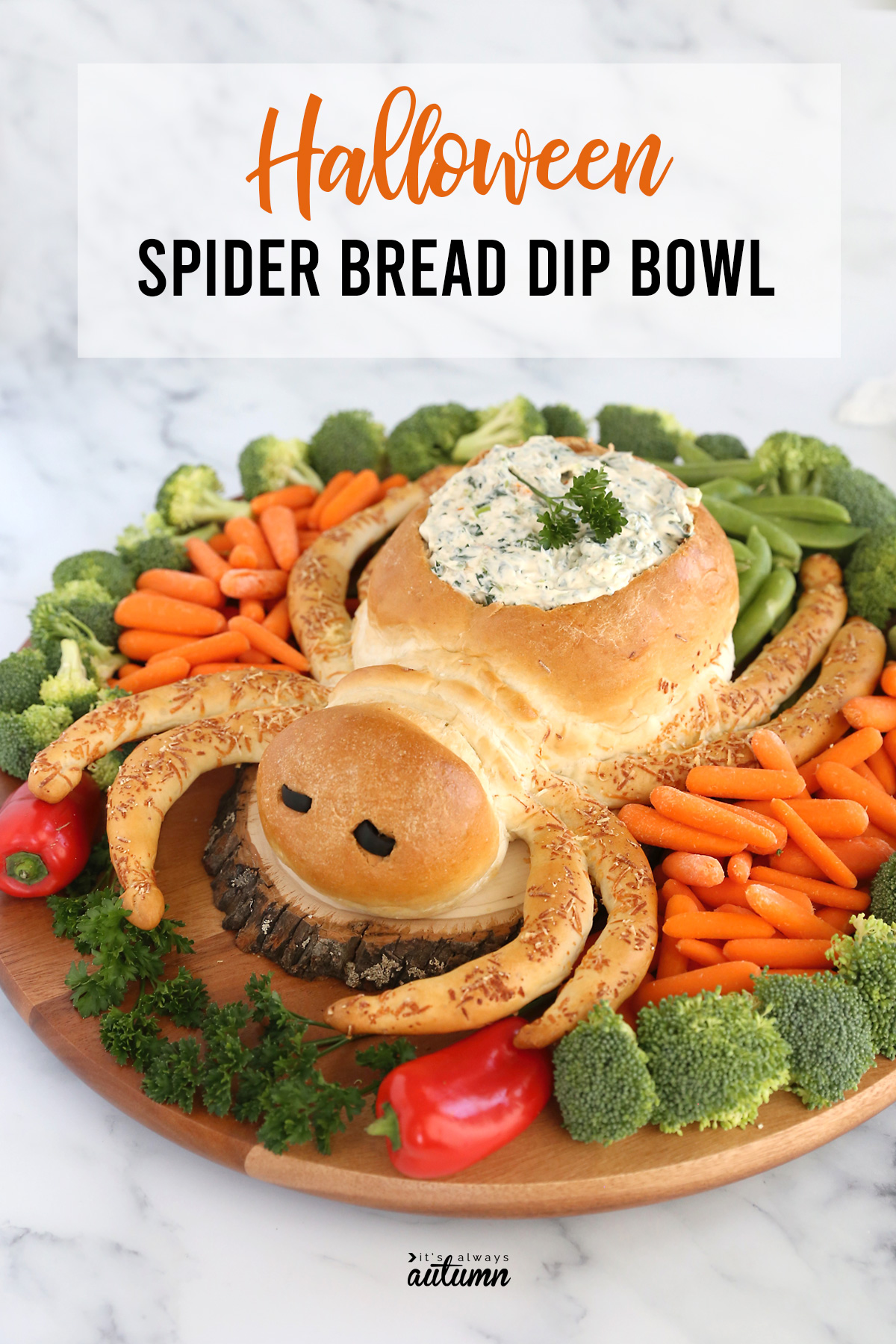 A loaf of bread shaped as a spider, with the center hollowed out and filled with dip, surrounded by vegetables
