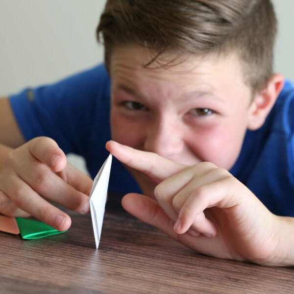 Boy ready to flick a folded paper football