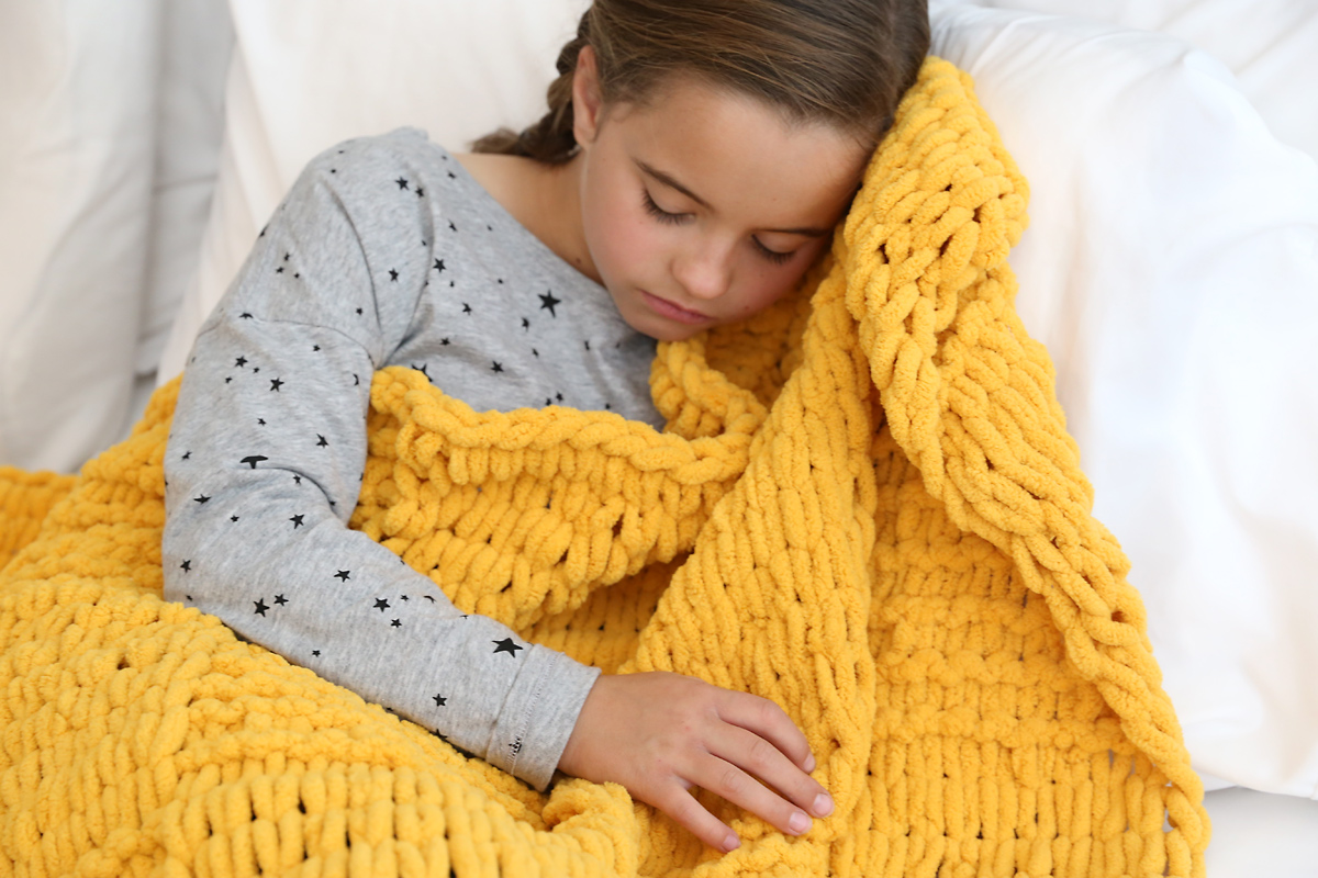 Girl sleeping with yellow loop yarn blanket
