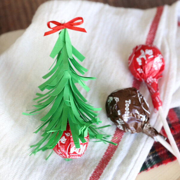 Tootsie pop sucker sitting upside down, with stick covered with strips of green paper to resemble Christmas tree