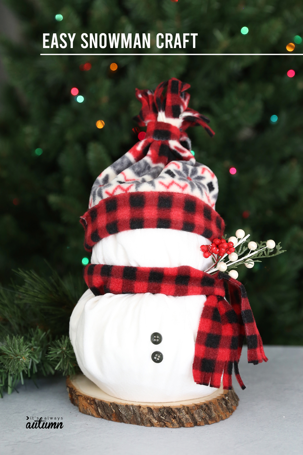 Snowman craft made from two rolls of toilet paper wrapped in white fabric with fleece scarf and hat