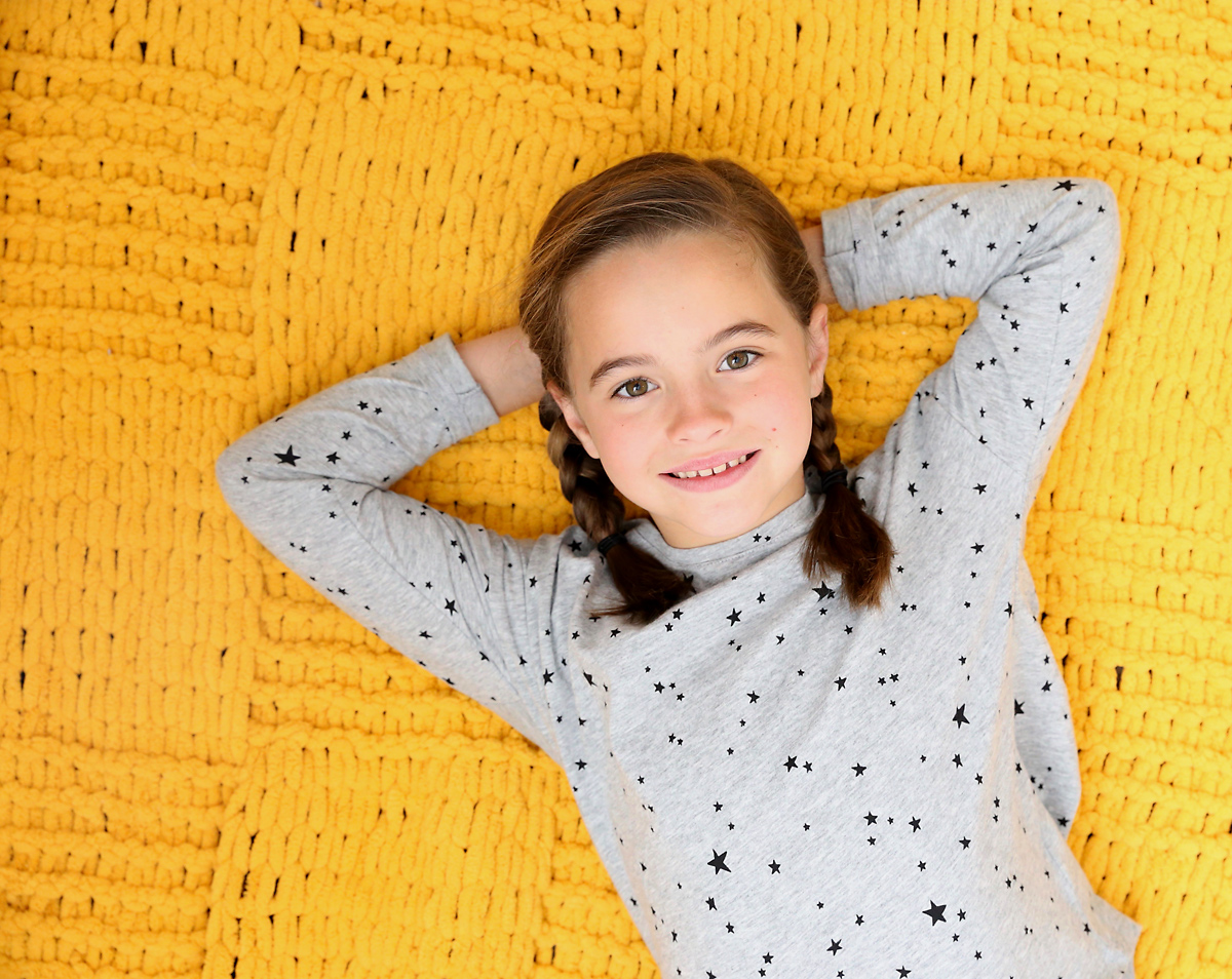 Girl laying on a yellow blanket made from loop yarn