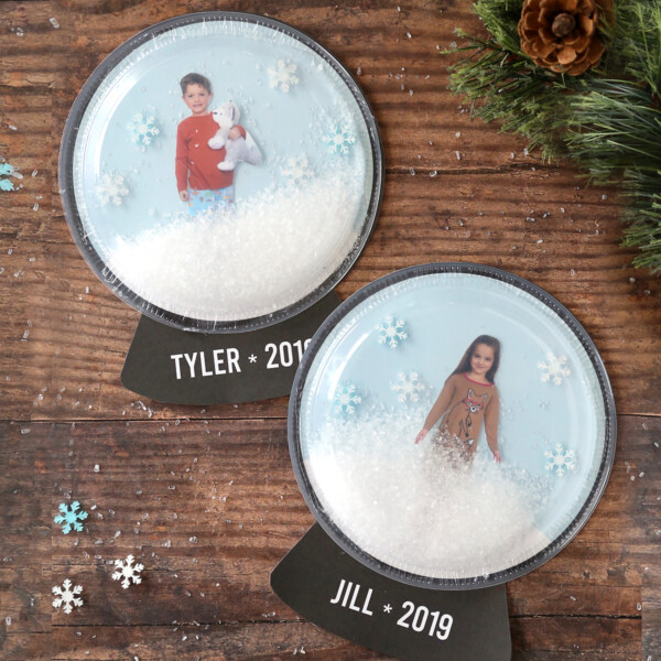 Snow globe craft made with clear plastic plates with pictures of children inside