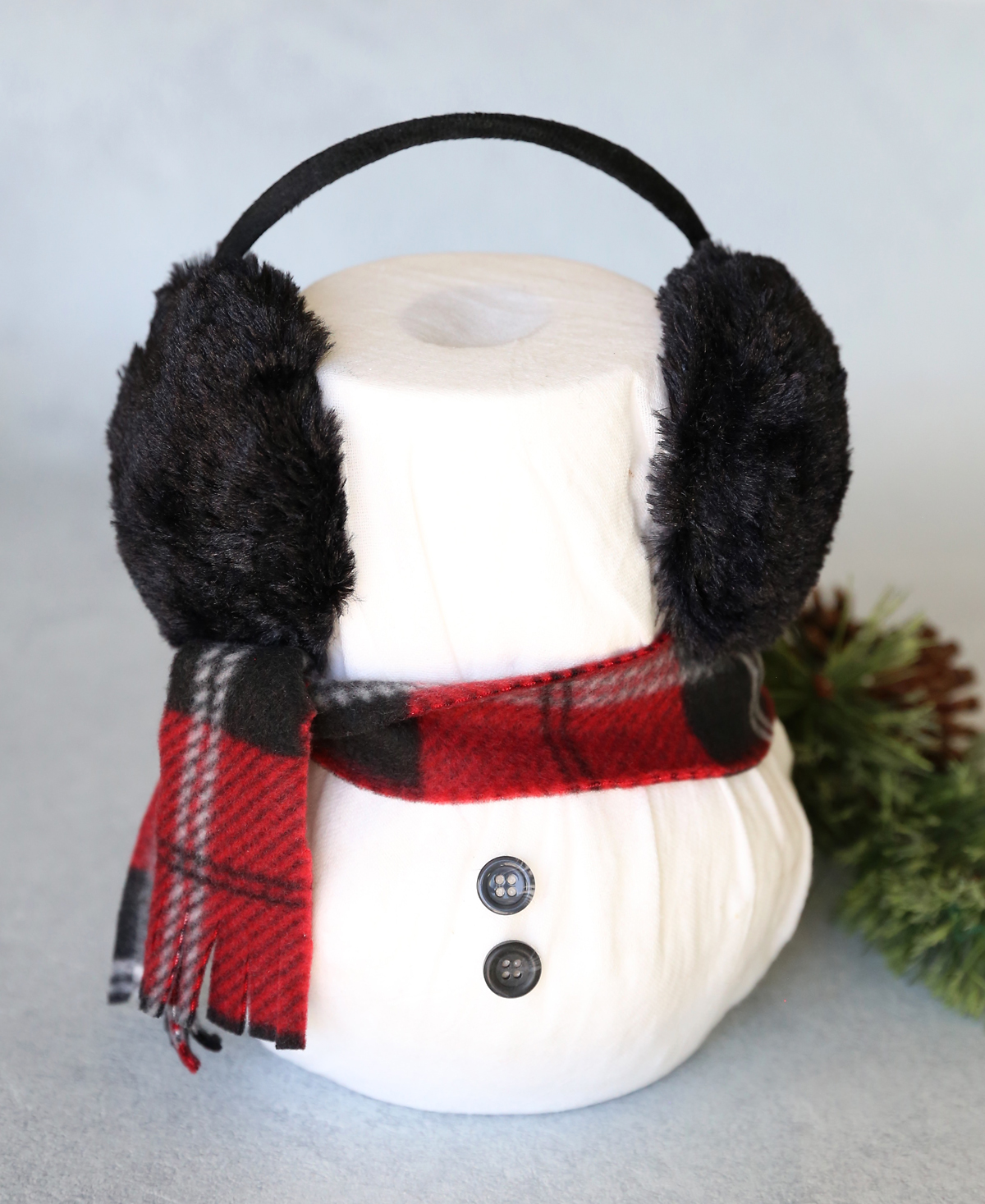Snowman made from two rolls of toilet paper with fleece scarf and earmuffs