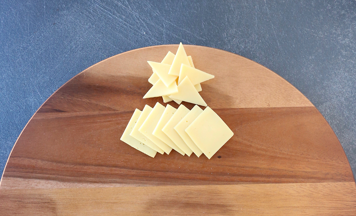 Cheese triangles arranged into star, with short row of white cheese slices layered beneath it