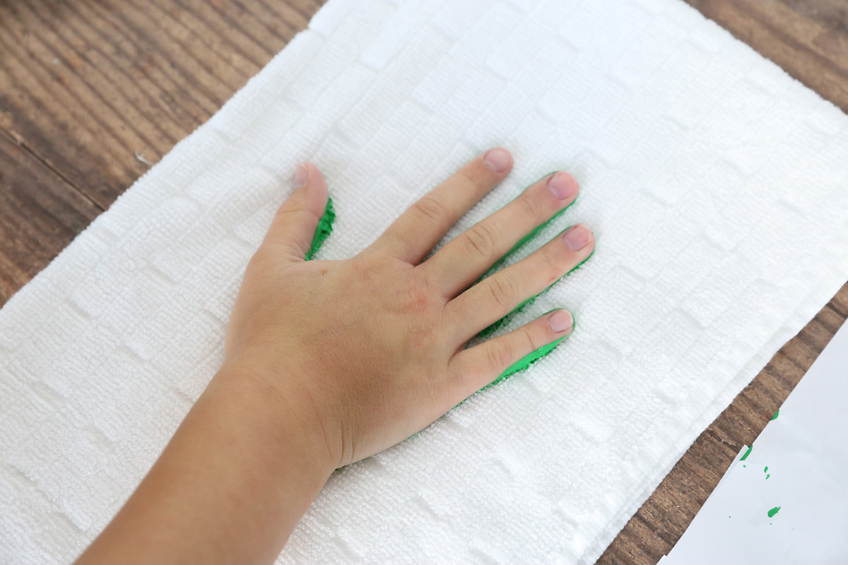 Place the painted hand down on the towel, creating and handprint