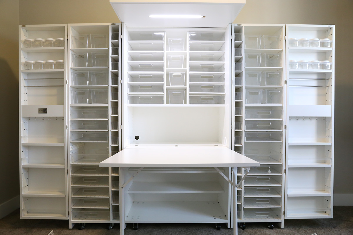 Wall sized craft storage system with multiple shelves and bins to hold supplies as well as a pull out table