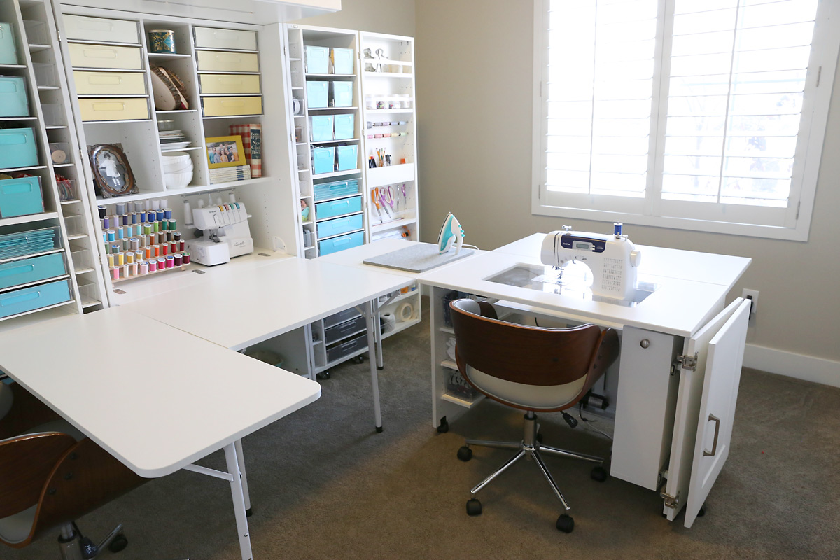 An office with a wraparound sewing desk and shelving for craft storage