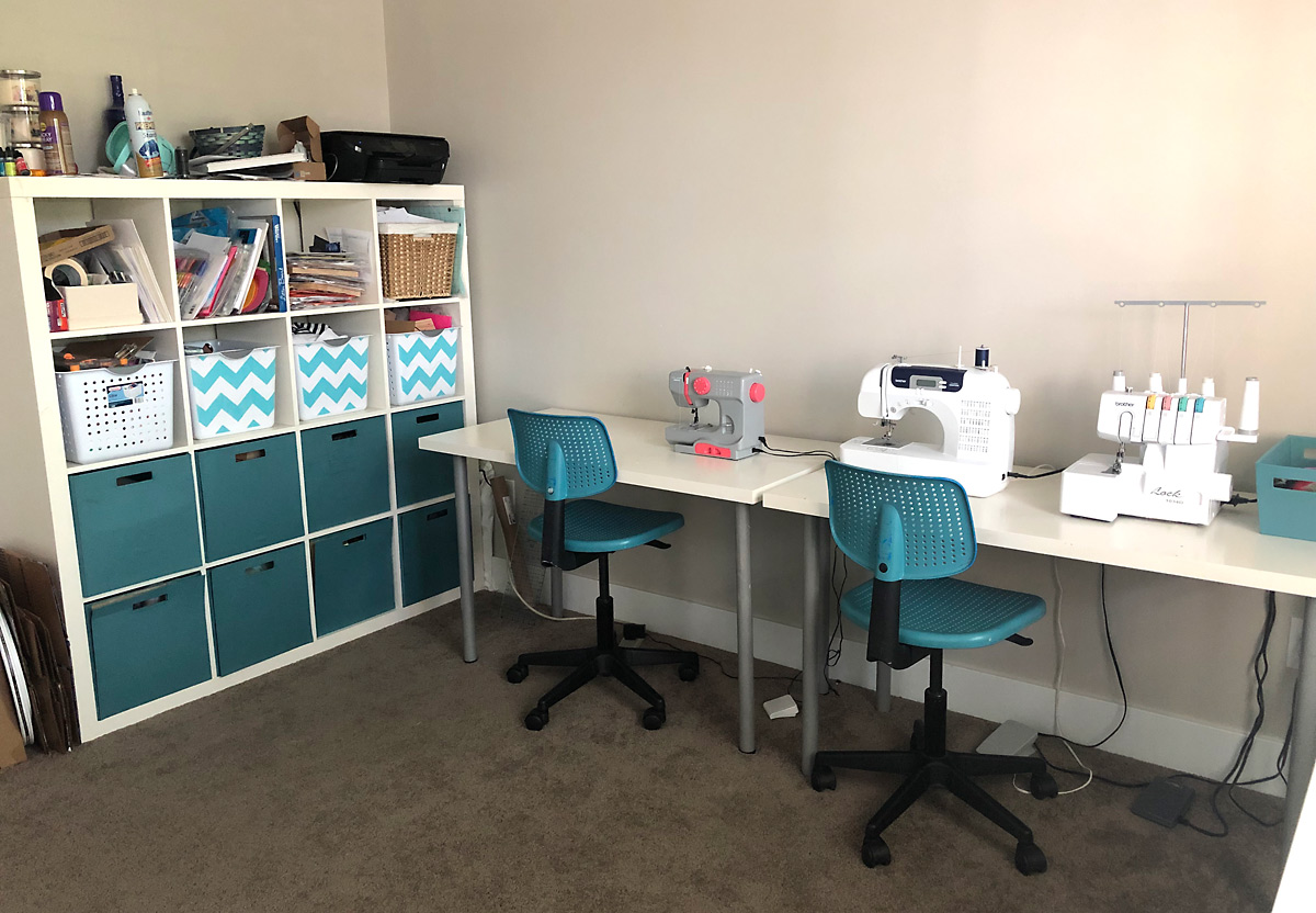 Tables along the side of a room with sewing machines on them and chairs