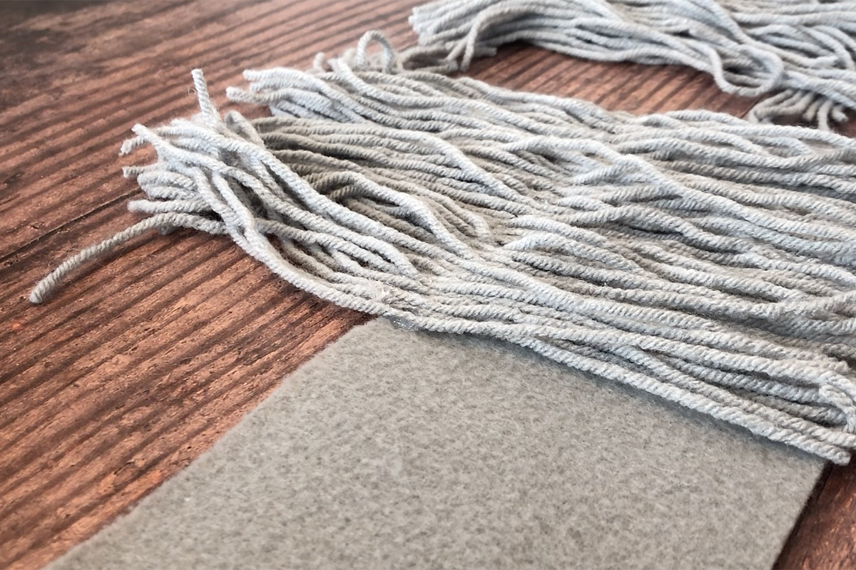 Grey yarn placed over strip of gray felt