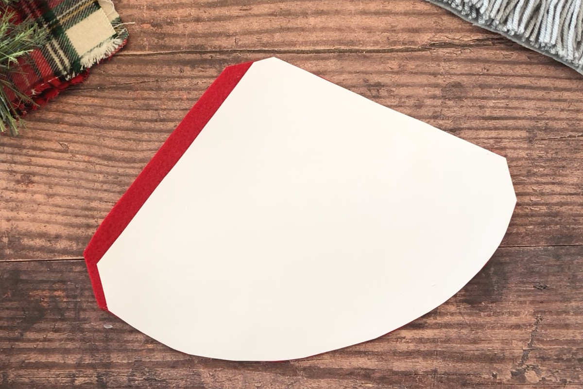 Triangle shape with rounded bottom edge placed over red felt to create gnome hat