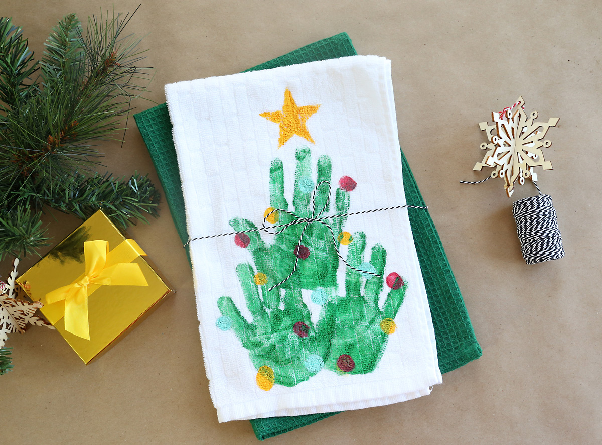 Kitchen towel with a handprint Christmas tree on it, tied with twine as a gift