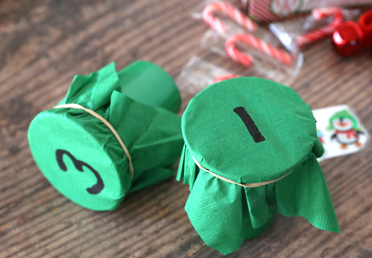 Cups with green napkins rubber banded around the top and numbers on them