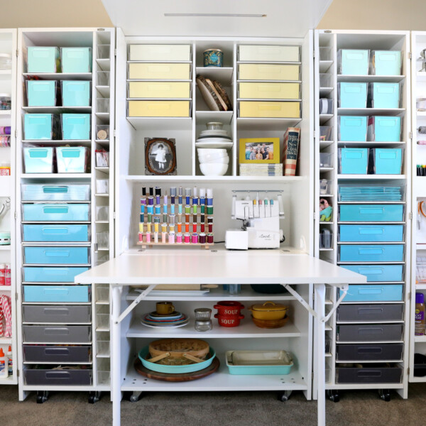 Wall sized craft storage system with multiple shelves and bins to hold supplies as well as a pull out table; full of color coordinated bins