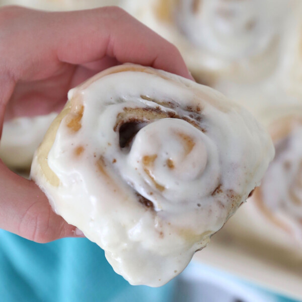 A hand holding a homemade cinnamon roll