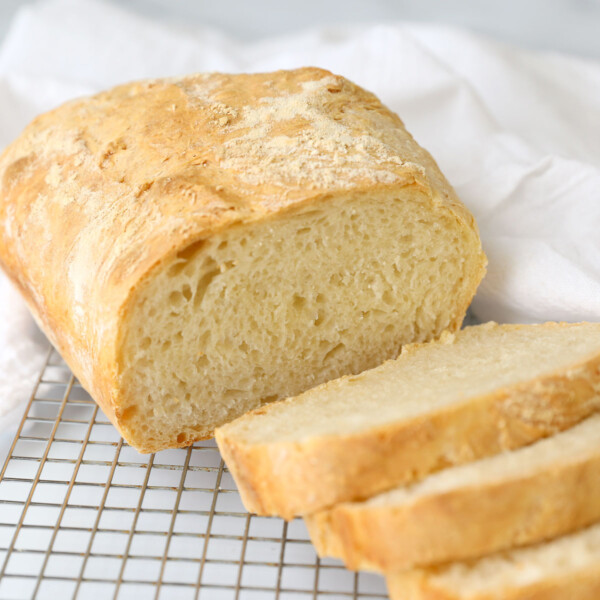 A loaf of 4 ingredient bread, sliced and resting on a cooling rack