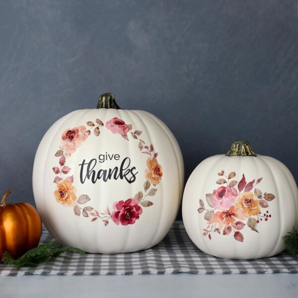 White craft pumpkins with floral designs and the words "give thanks" on them