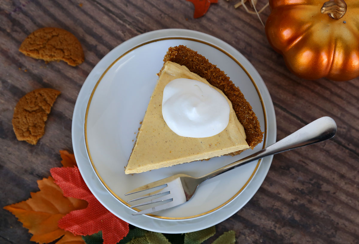 Slice of no bake pumpkin cheesecake on a white plate with whipped topping and a fork