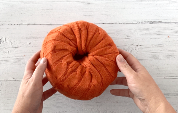 Sweater sleeve tucked into either end of a roll of toilet paper to create a pumpkin