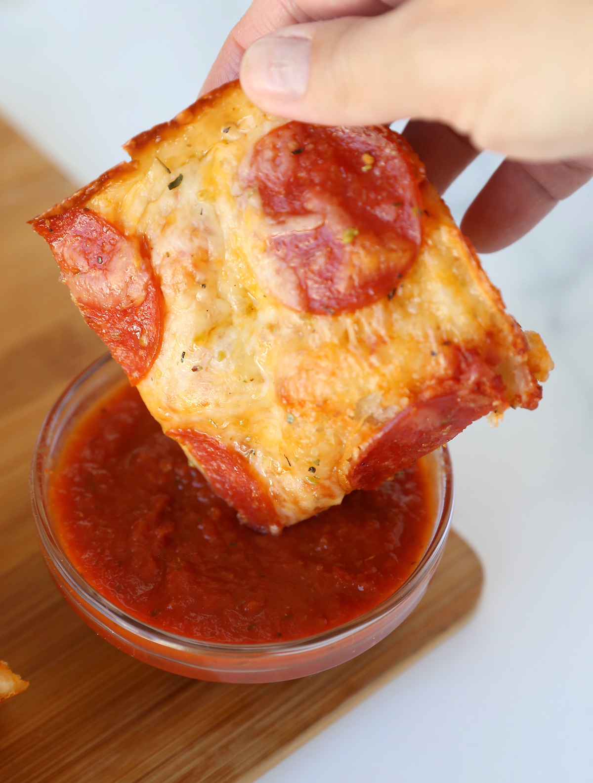 Dipping deep dish pan pizza into extra pizza sauce