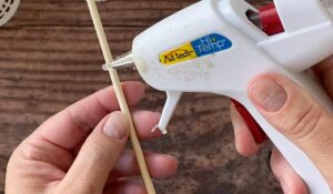 Place hot glue at lowest mark on skewer