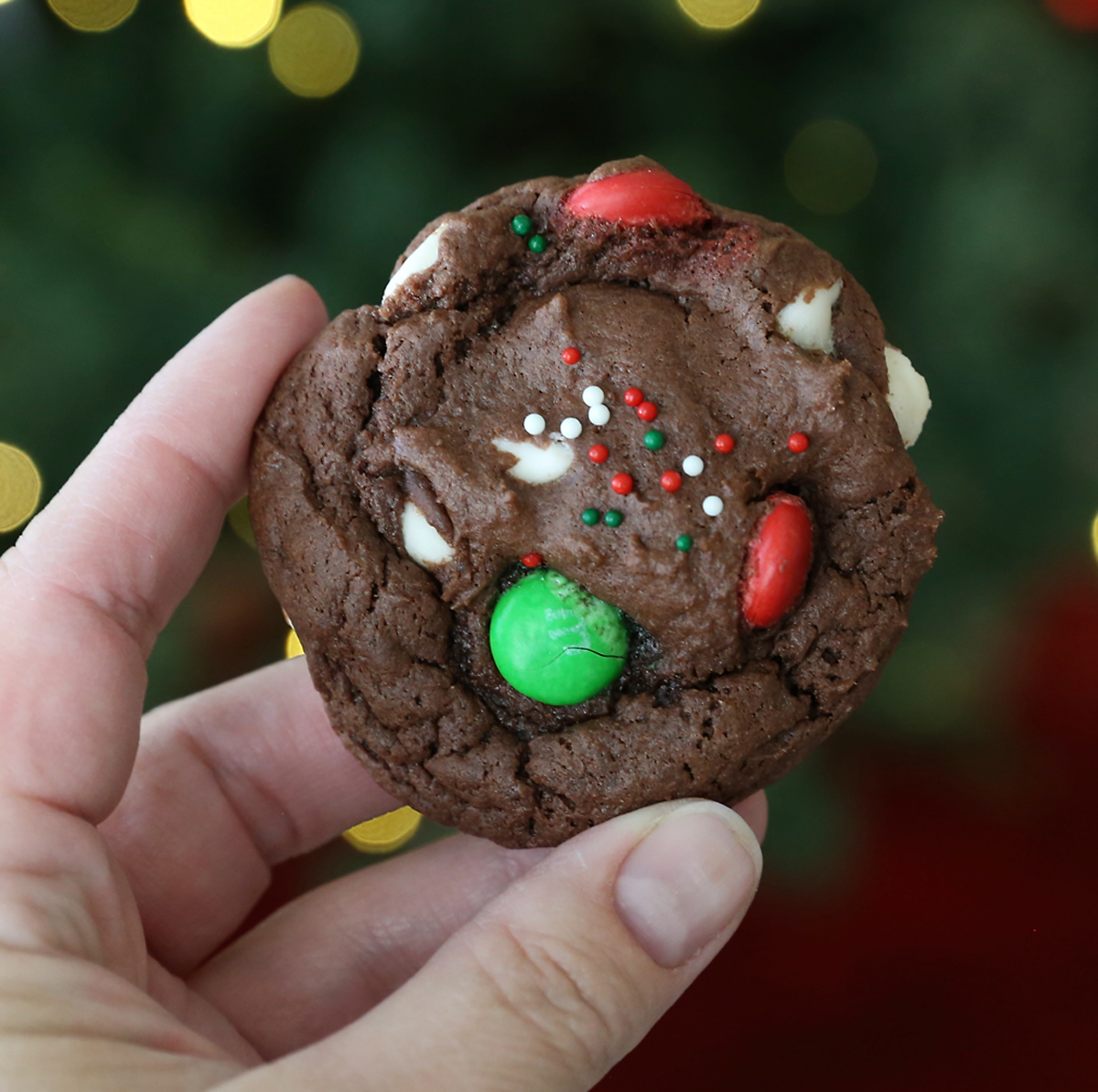 Hand holding a chocolate cookie with red and green M+Ms