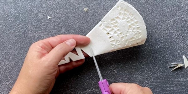 Paper doily triangle being cut from one straight side