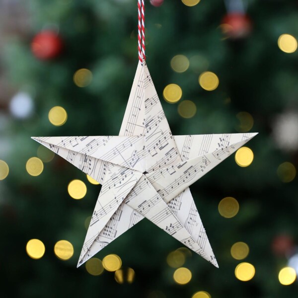 Paper origami star in front of a Christmas tree