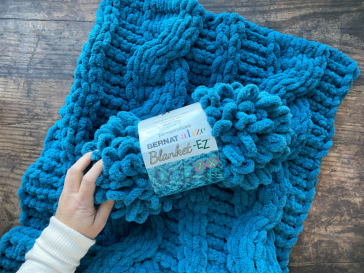 Ball of turquoise loop yarn and finger knit blanket.