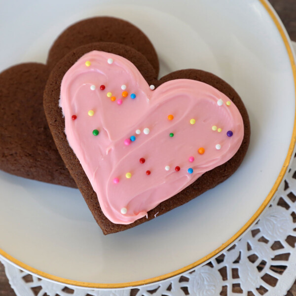 Heart shaped chocolate sugar cookie with pink frosting and sprinkles