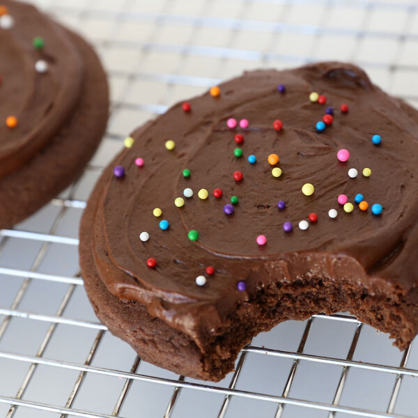 Chocolate sugar cookie with chocolate frosting and sprinkles with a bite taken out of it