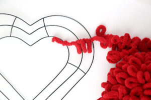 Red loop yarn with one end tied to a wire heart shaped wreath form