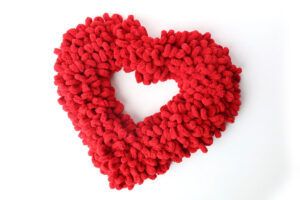 Heart shaped wreath covered in fluffy red loops of yarn