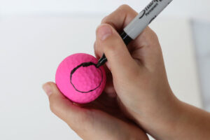 Hand drawing black circle on a pink golf ball