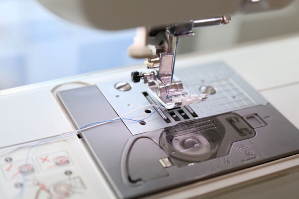 Sewing machine with blue thread in the needle and white elastic thread in the bobbin