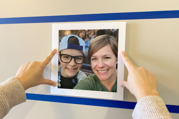 Hands pressing a photo board onto a wall in between rows of painters tape