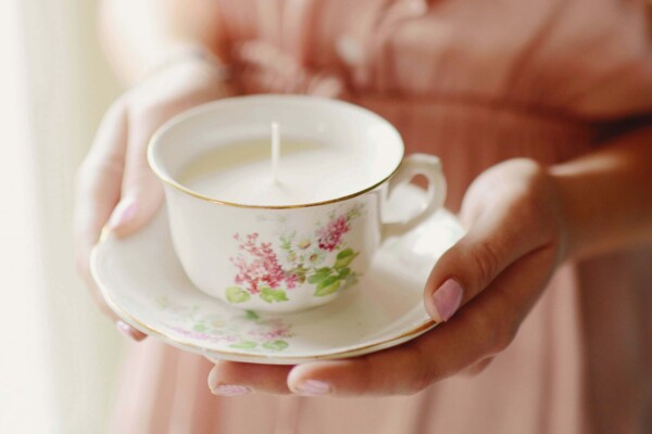 Hands holding teacup candle
