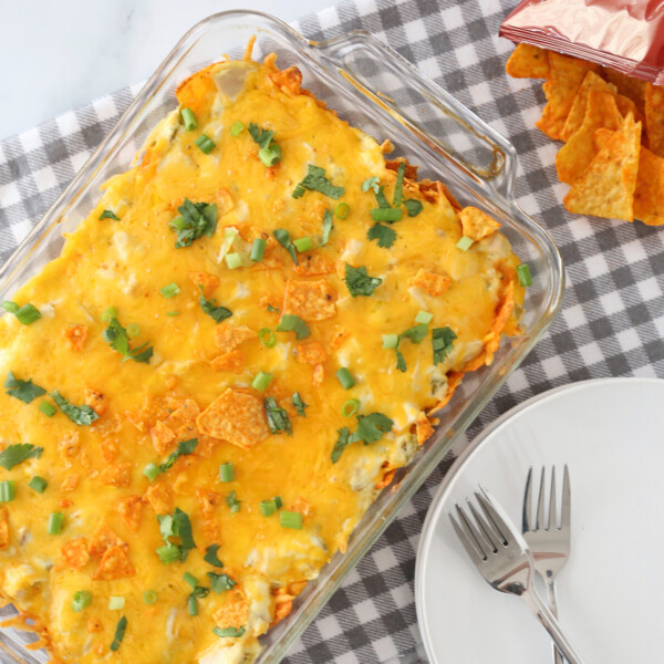 Creamy doritos enchilada casserole in a glass dish with a plate and forks