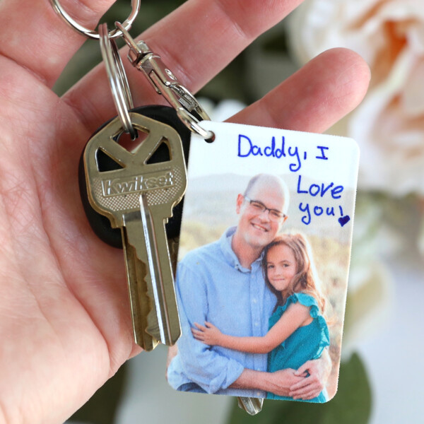 Hand holding keychain with picture of a little girl and her dad that says: Daddy I love you!