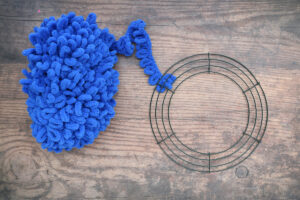 Blue loop yarn with one end tied to a wire wreath frame
