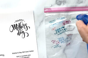 Hand spraying water onto the ink on a ziplock bag
