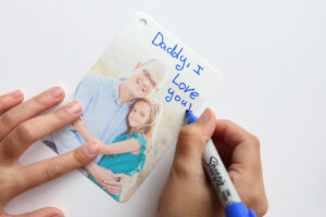 Child writing "Daddy, I love you!" on a photo