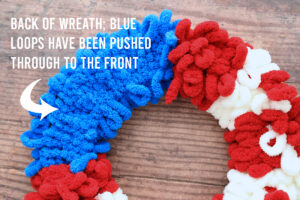 Back of loop yarn wreath with words: back of wreath; blue loop yarn have been pushed through to the front