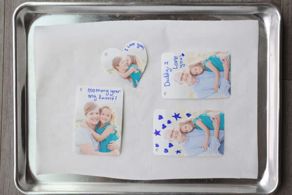 Photos with notes written on them on a parchment paper lined cookie sheet