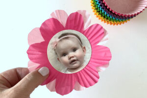 Two cupcake liners cut into flower shape layered on top of each other, with circular baby photo in the center