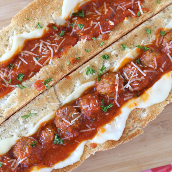 Two large meatball sandwiches on a cutting board