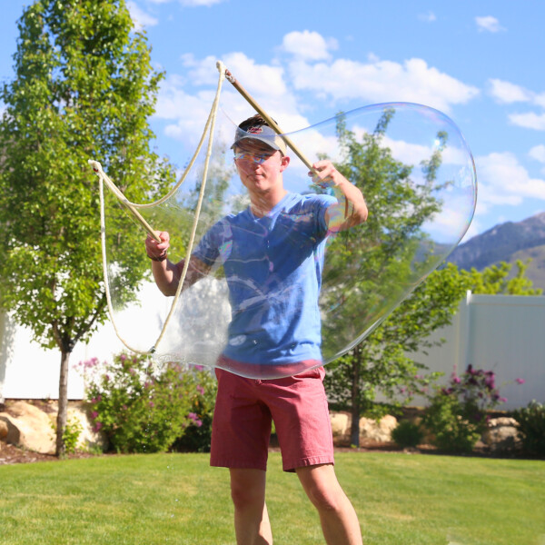 Boy holding DIY bubble wand to blow giant bubbles