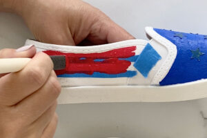 Painting red stripes on a canvas shoe