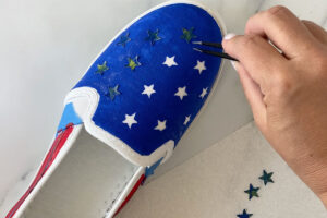 Removing star stickers from top of painted shoe with tweezers