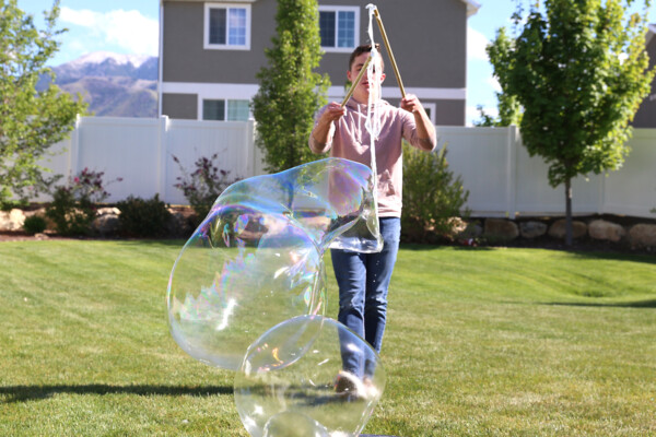 Boy holding DIY bubble wand with sticks back together to close off bubble